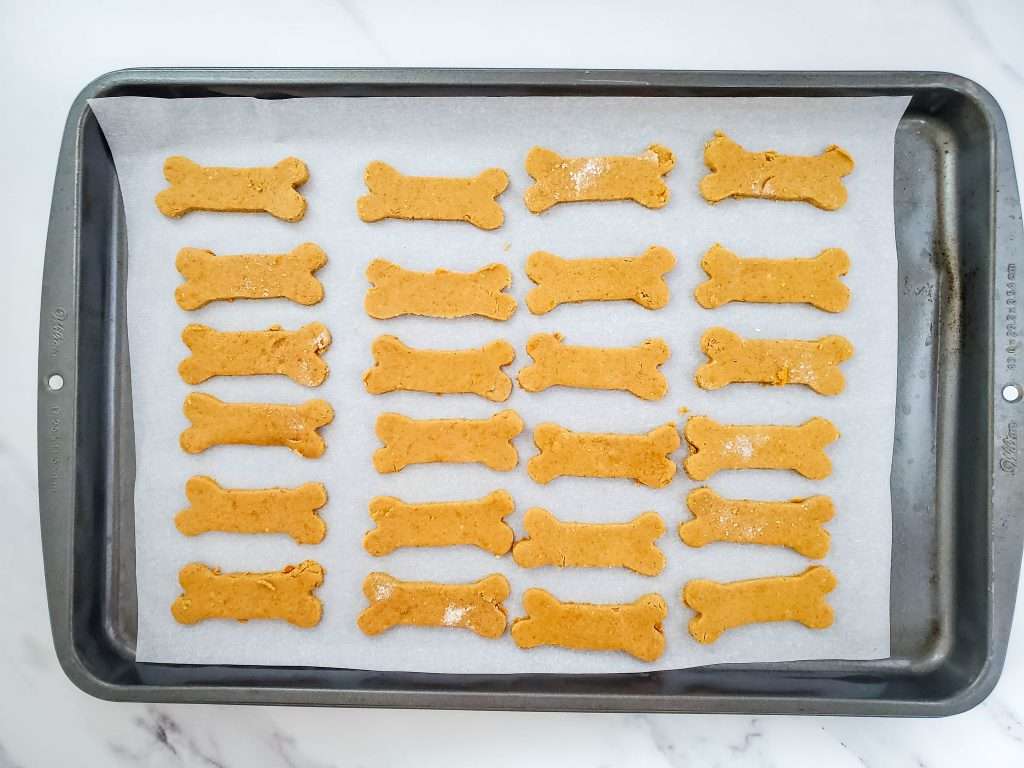 Baking tray lined with parchment paper with 3 ingredient dog treats ready to be baked.