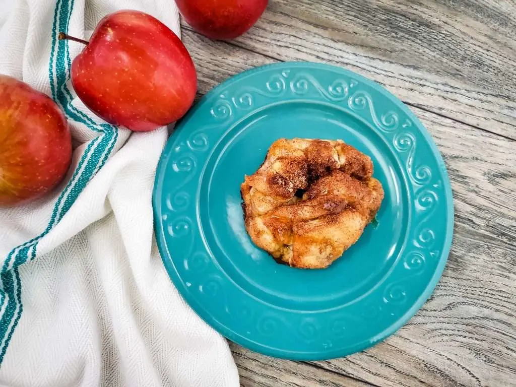 mini apple pie bomb on a blue plate with apples next to it 