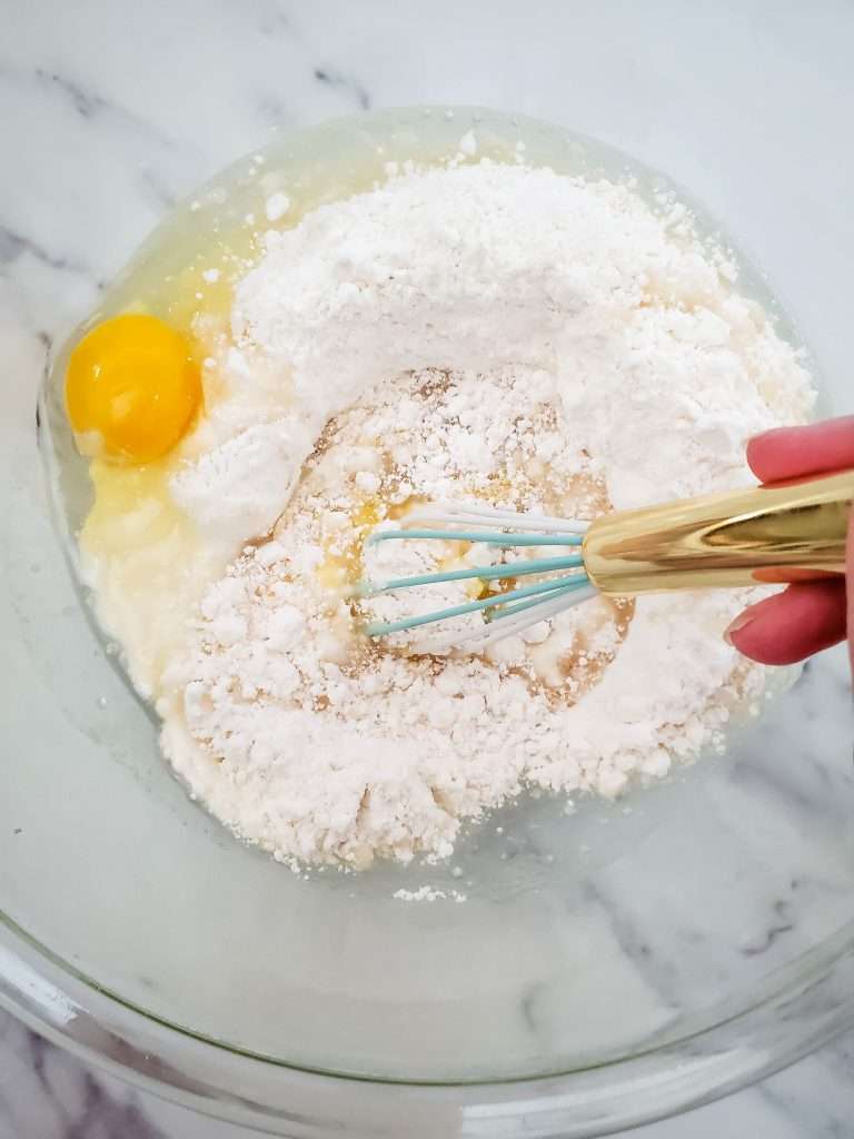 Bowl with white cake mix, eggs, and oil with whisk.