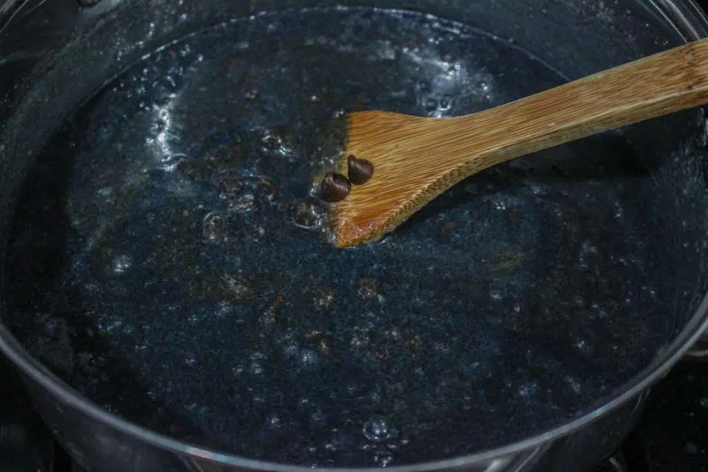 creating black food coloring in pan with wooden spoon 