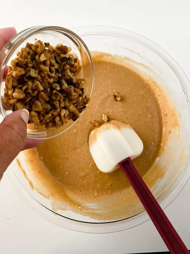 Apple Cider Cupcakes batter in a mixing bowl, small bowl of chopped walnuts being added to the mixture.