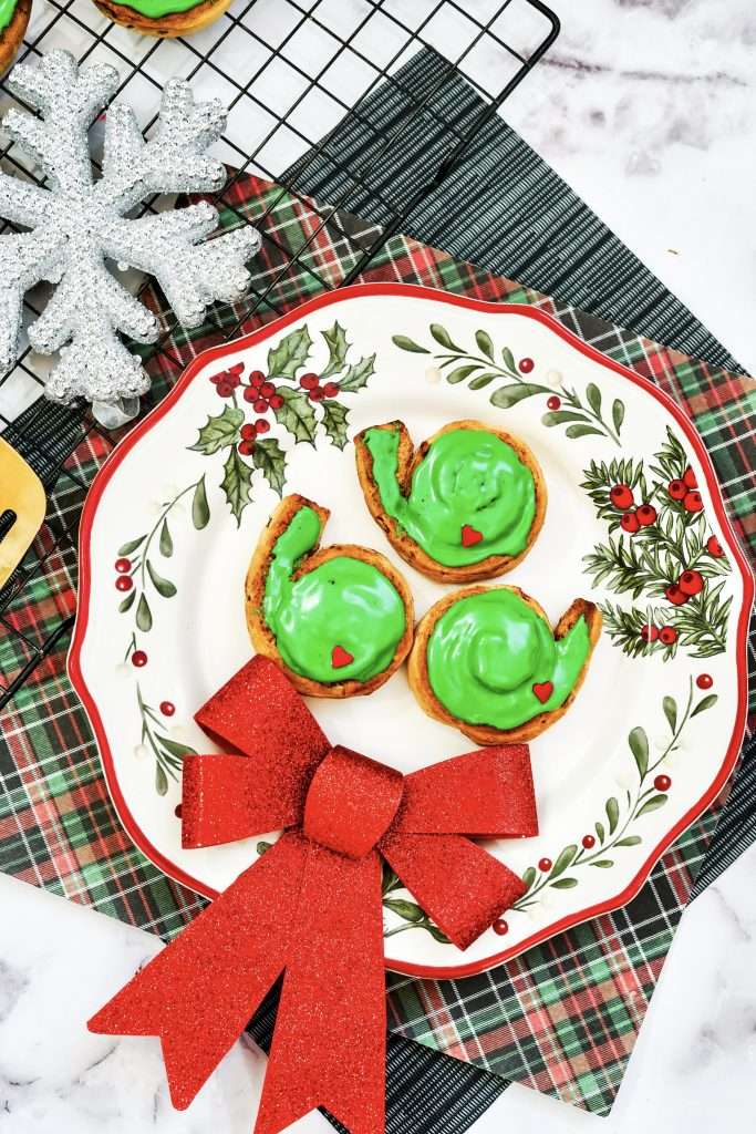 Grinch Christmas Cinnamon Rolls on a plate with a christmas bow