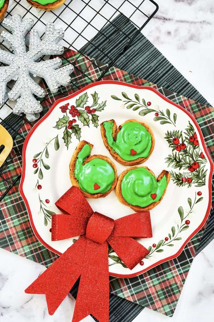 Grinch Christmas Cinnamon Rolls 8 Grinch Christmas Cinnamon Rolls on a plate with a christmas bow