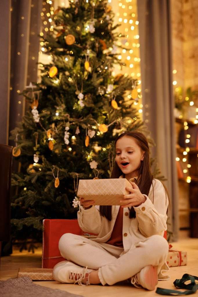 25 Stocking Stuffer Ideas for Kids Under 7 8 girl opening a christmas present under the christmas tree