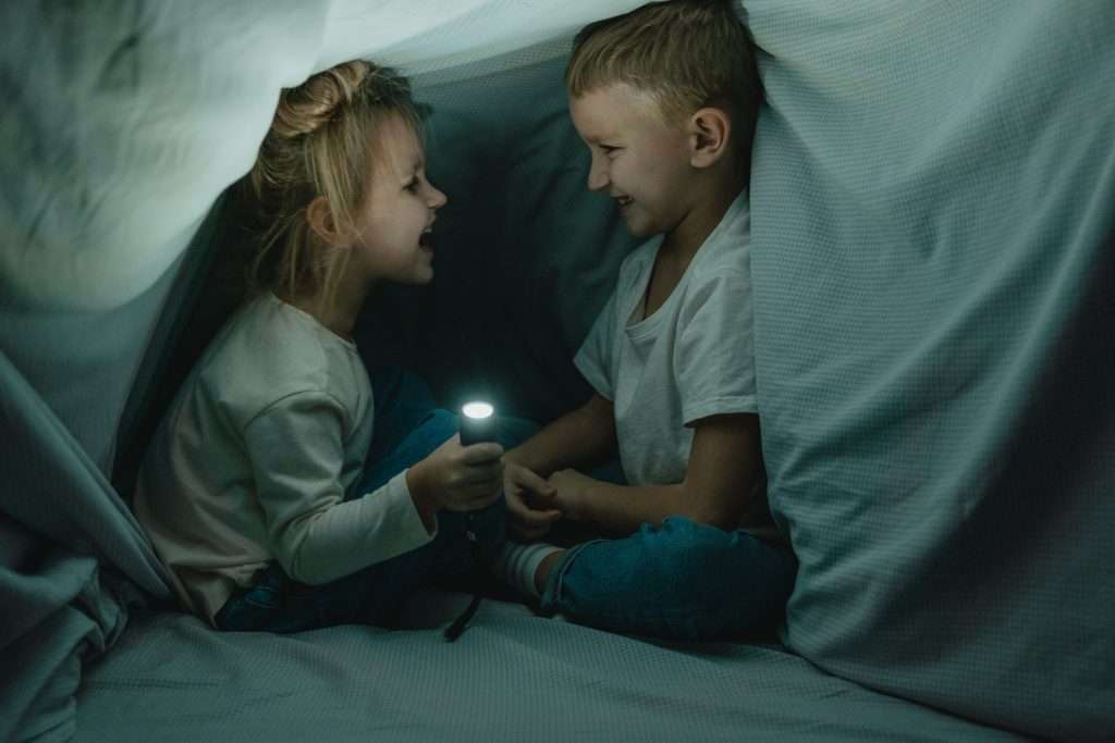 10 Free Winter Family Activities 7 little girl and little boy playing under the covers with a flashlight