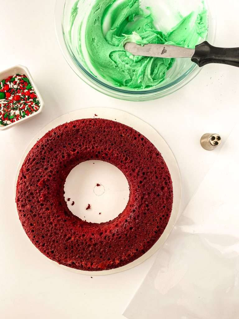 round red velvet cake with green icing and christmas sprinkles