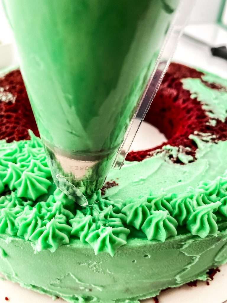 Buttercream Christmas Wreath Cake From Cake Mix 9 close up of piping green frosting onto red velvet cake