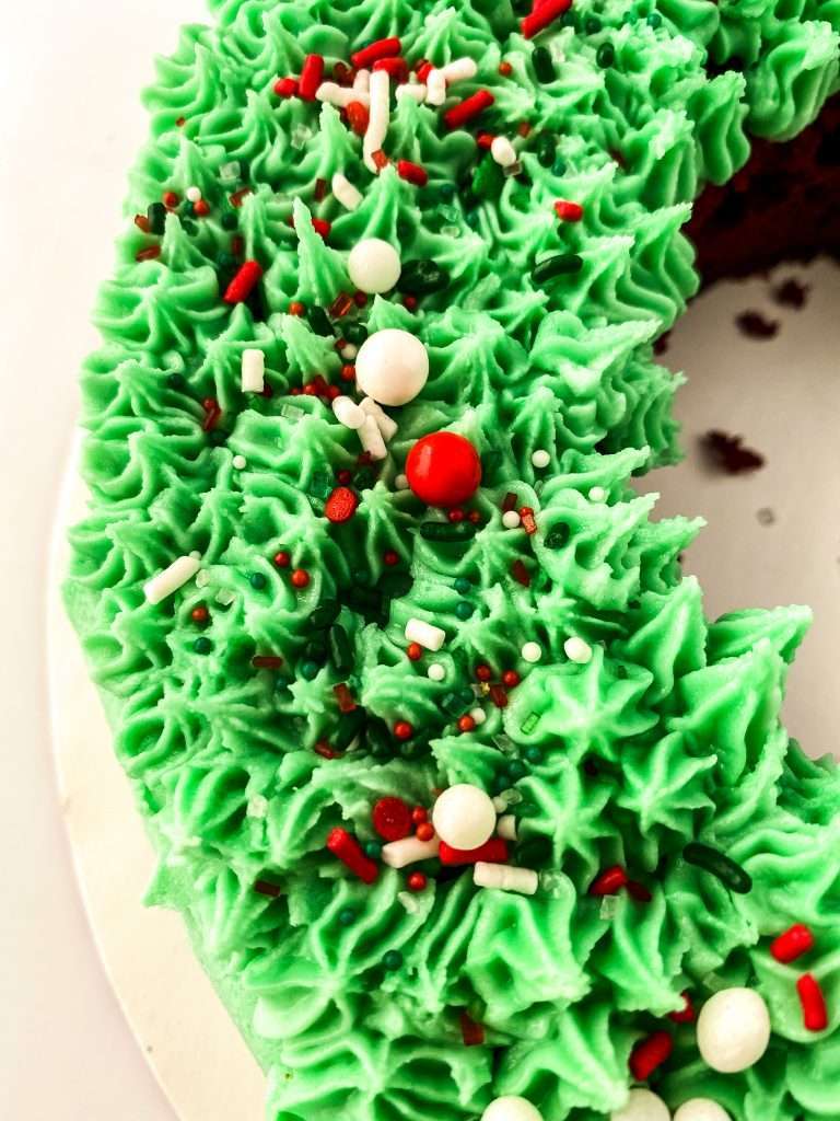 Buttercream Christmas Wreath Cake From Cake Mix 10 close up view of cake with green frosting and red and white holiday sprinkles