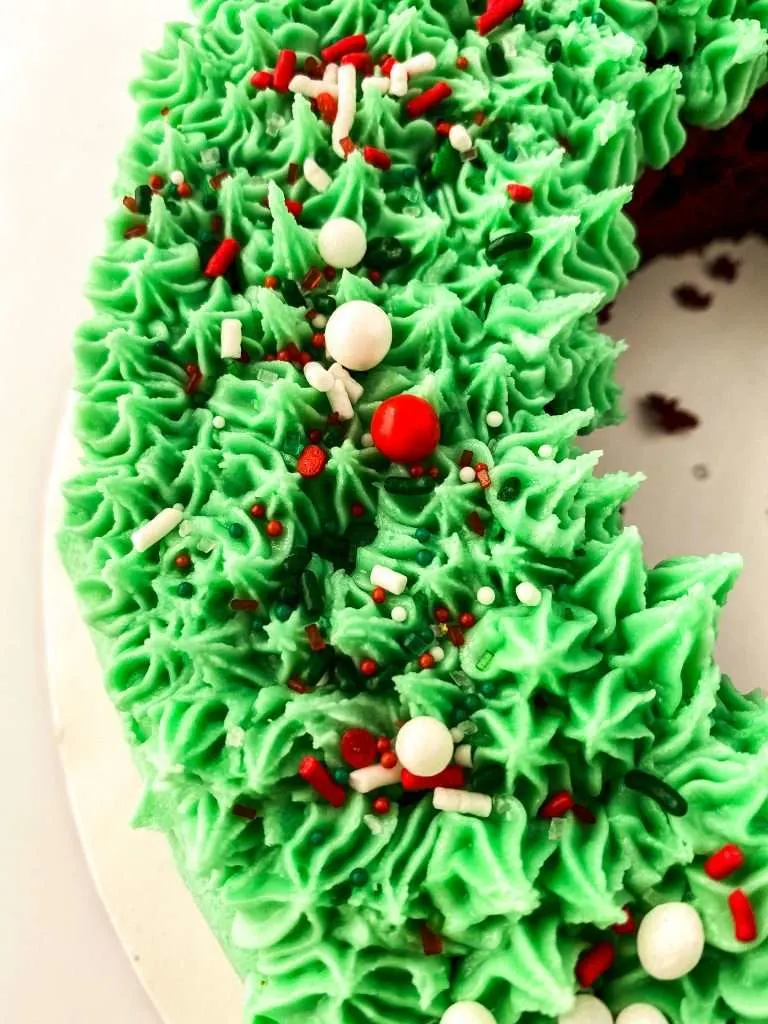 close up view of cake with green frosting and red and white holiday sprinkles 