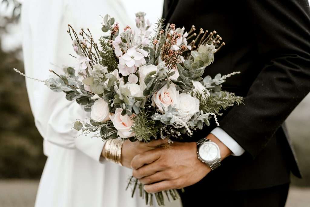 How to Plan a Vow Renewal 4 couple holding hands and a bouquet of flowers