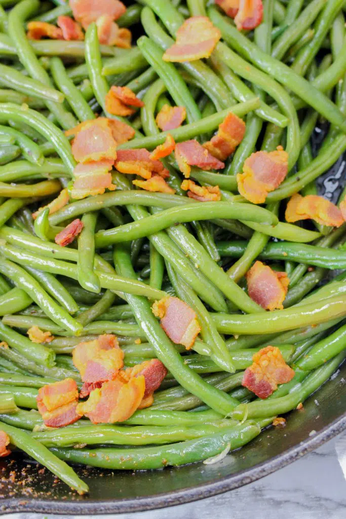 close up of fresh green beans with bacon in a pan