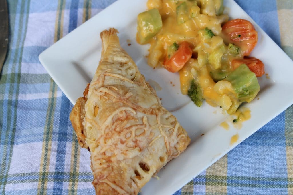 overhead view of chicken turnover with vegetables on white plate 