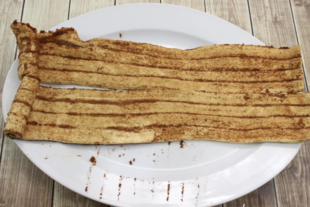 Pumpkin Cinnamon Rolls (3 Ingredients) 11 Cinnamon rolls unrolled on white plate.