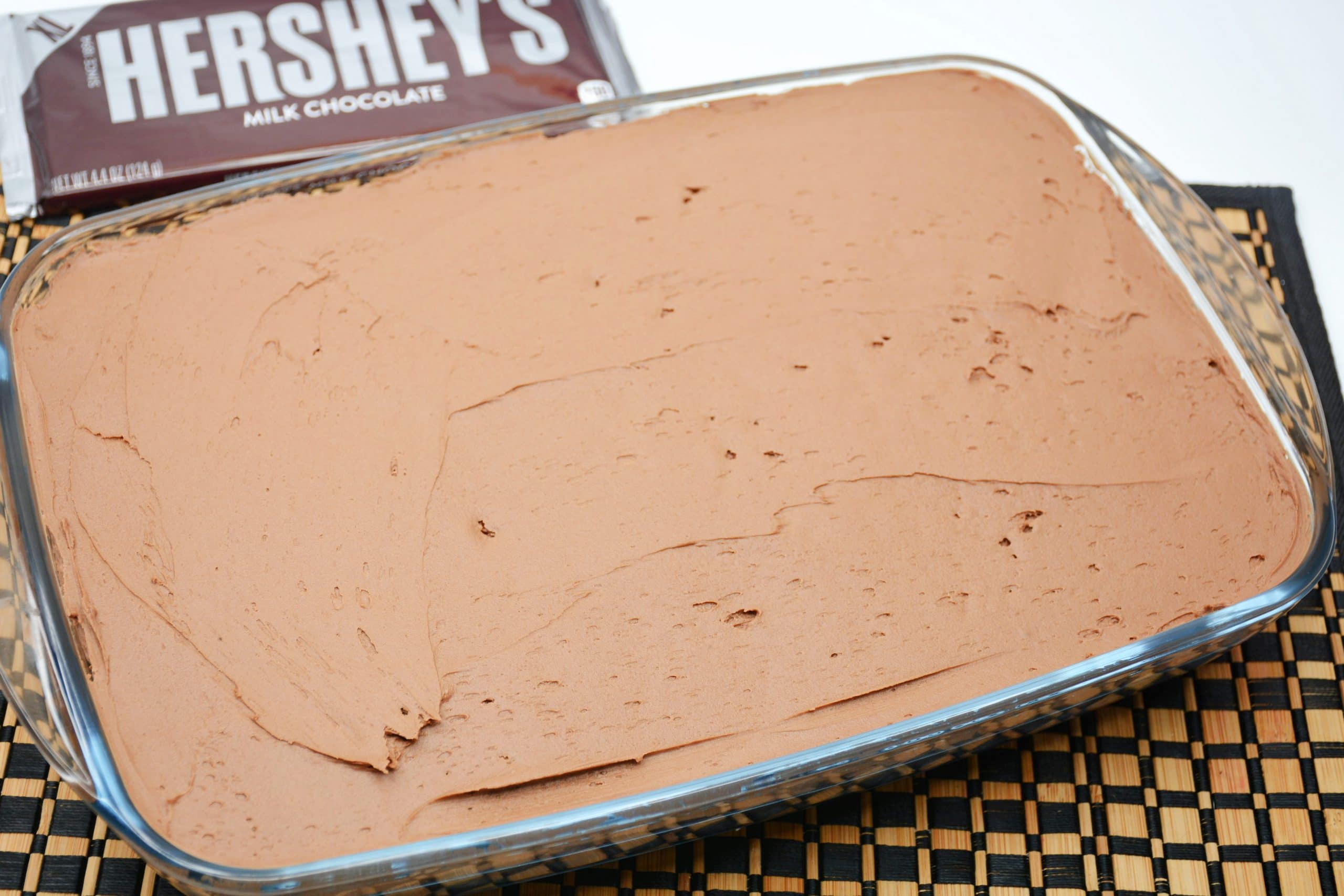 Hershey's Chocolate Cake frosted Hershey's chocolate cake in cake pan with Hershey's bar next to it