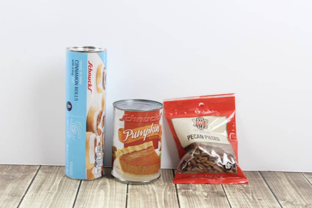 Pumpkin Cinnamon Rolls (3 Ingredients) 8 3 Ingredient Pumpkin Cinnamon Roll ingredients on wood layout with white background.