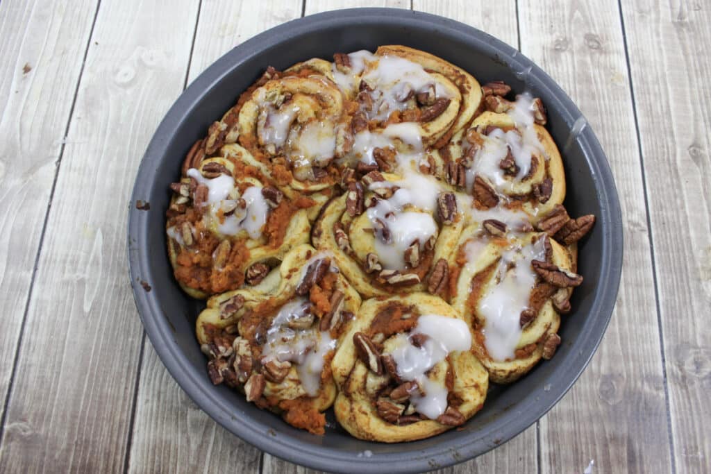Pumpkin Cinnamon Rolls (3 Ingredients) 15 Round pan of pumpkin cinnamon rolls topped with icing and pumpkin spice frosting.