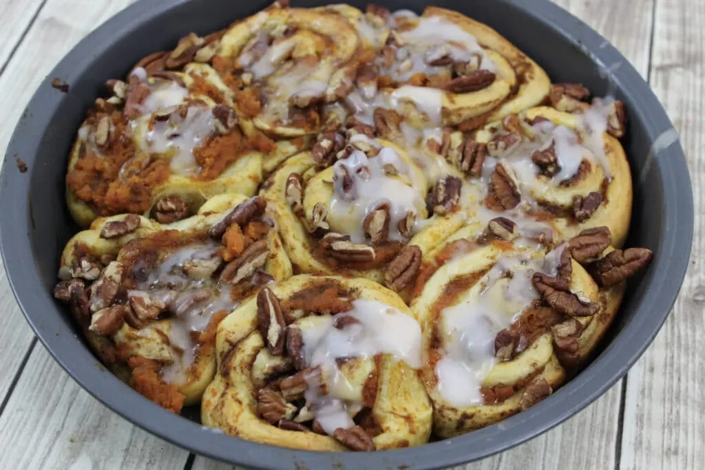 3 Ingredient Pumpkin Spice Cinnamon Rolls baked in round pan topped with icing. 