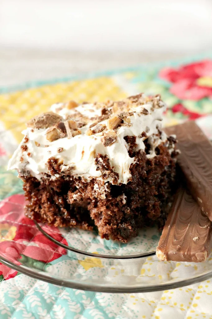 A slice of heath bar cake on a clear plate. 