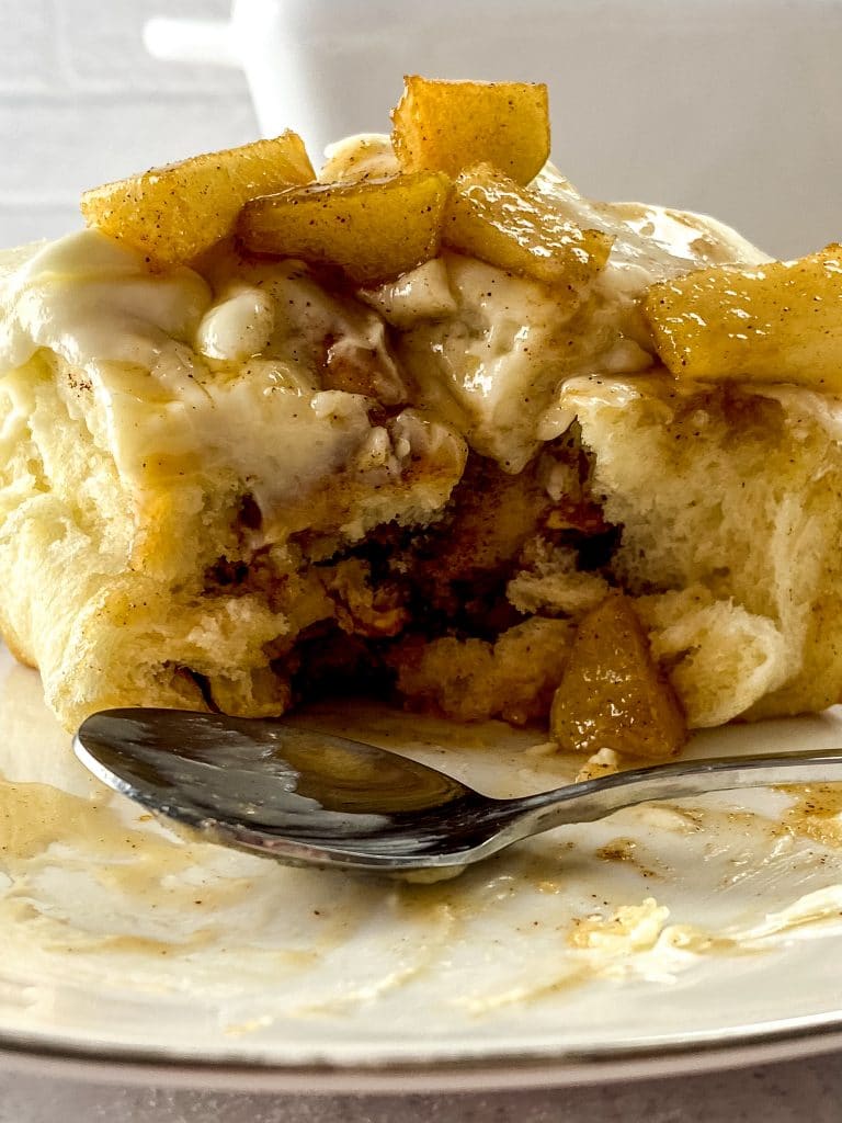 close up of apple pie cinnamon roll with silver spoon