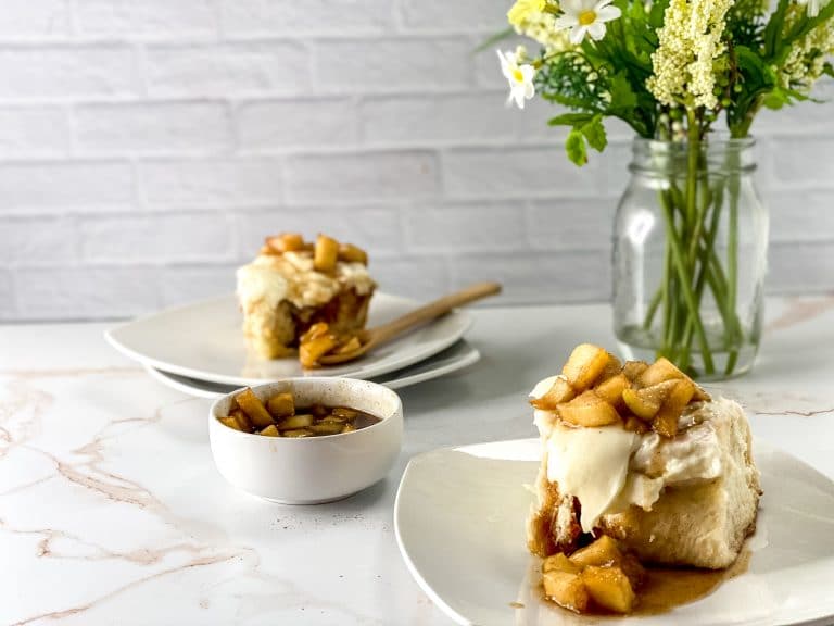 apple pie cinnamon roll on white plate with flowers in background