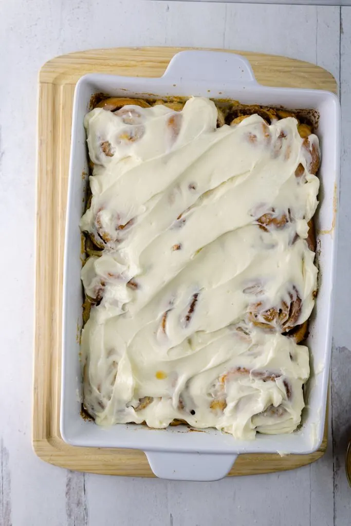 apple pie cinnamon rolls covered with cream cheese in white dish 