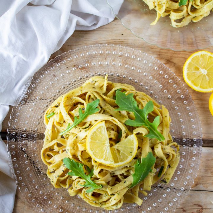 one pot lemon pasta on a clear plate with lemon on top