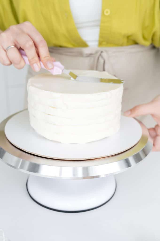 adding frosting to a cake
