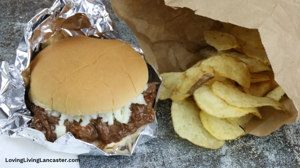 pulled venison sandwich with chips in paper bag