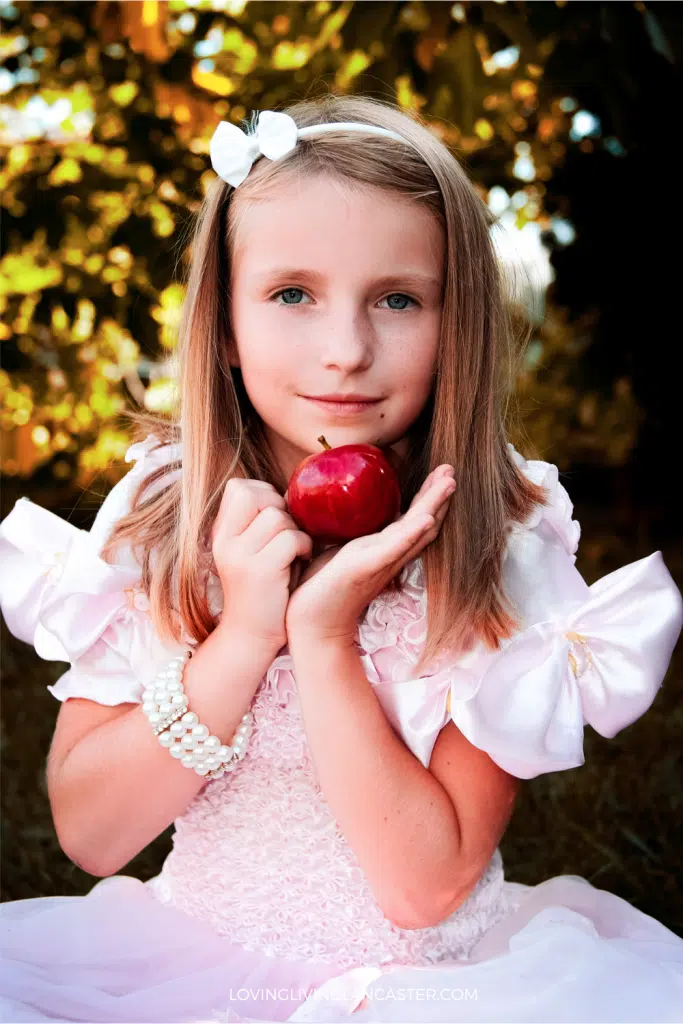girl holding apple under her chin