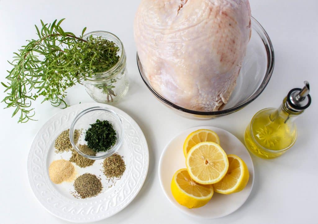 overhead view of lemon and herb turkey breast ingredients on white plates and in clear bowls 