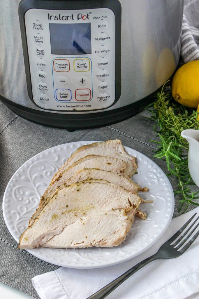Quick Instant Pot Lemon and Herb Turkey Breast Recipe 3 sliced lemon and herb turkey breast with herbs, lemon and an Instant Pot in the background