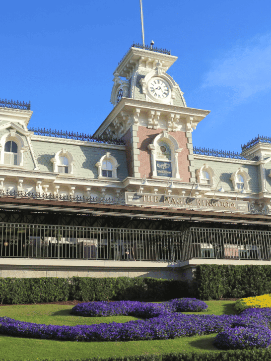 Magic Kingdom Train Station with purple and yellow flowers in front 