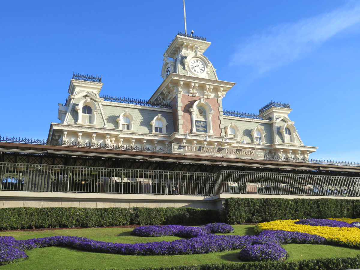 Magic Kingdom Train Station with purple and yellow flowers in front