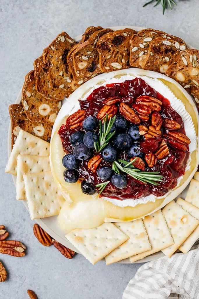 baked Brie with cranberries, blueberries and nuts with crackers on the side 