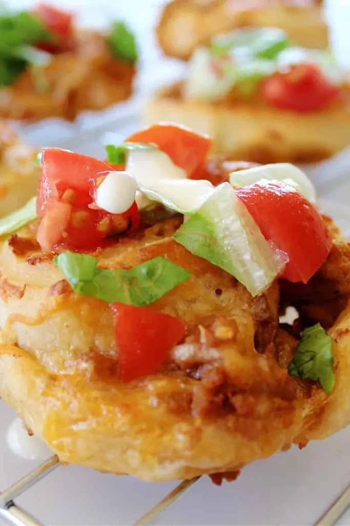 close up of taco roll up with pizza crust, tomatoes and lettuce 