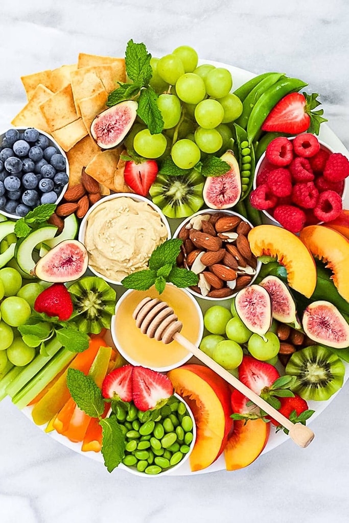 charcuterie board topped with fruit, veggies and nuts 