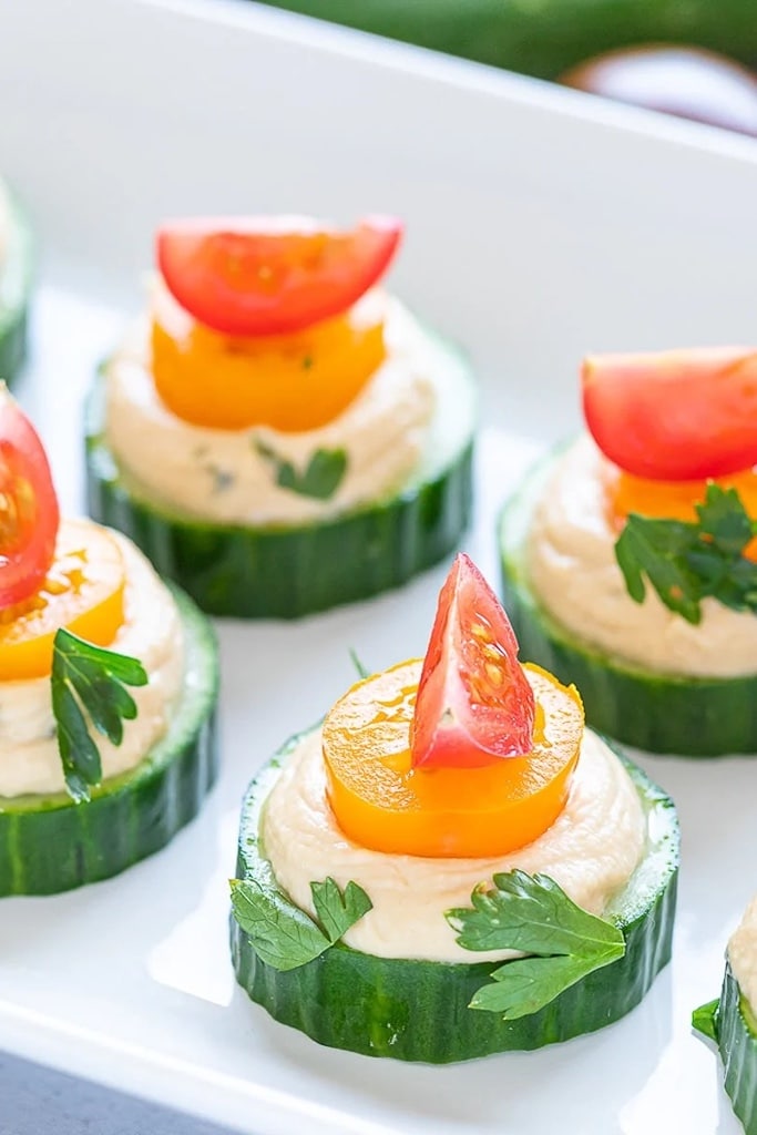 cucumber topped with hummus, tomato and parsley 