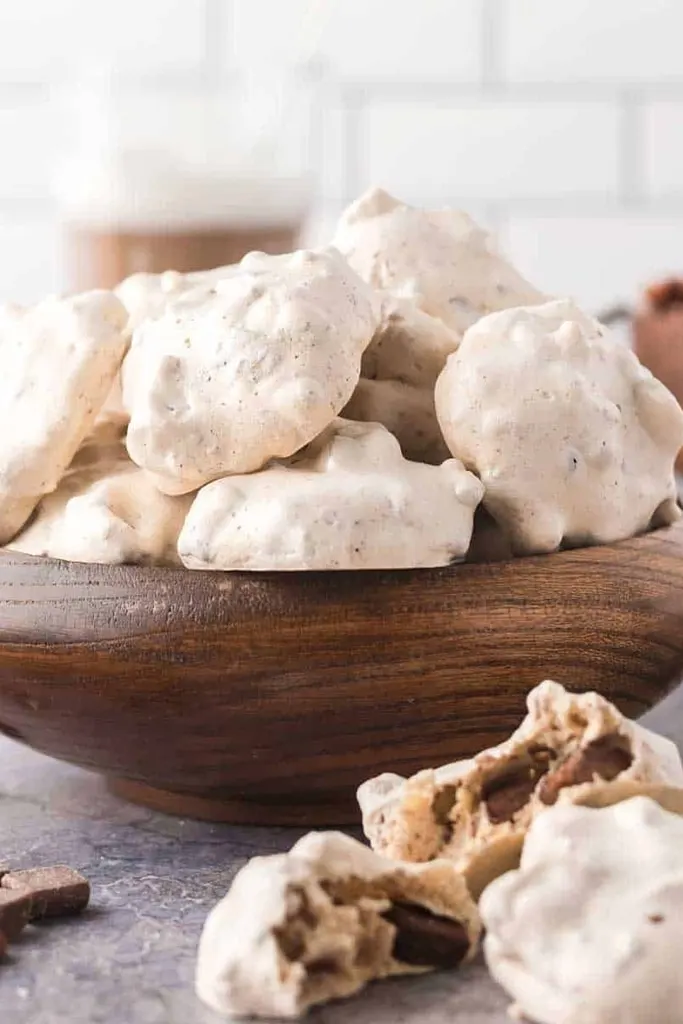 stack of white cookies on wooden serving bowl with one broken open 