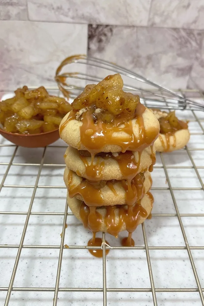 stack of apple pie cookies on cooling rack with caramel running down on them 