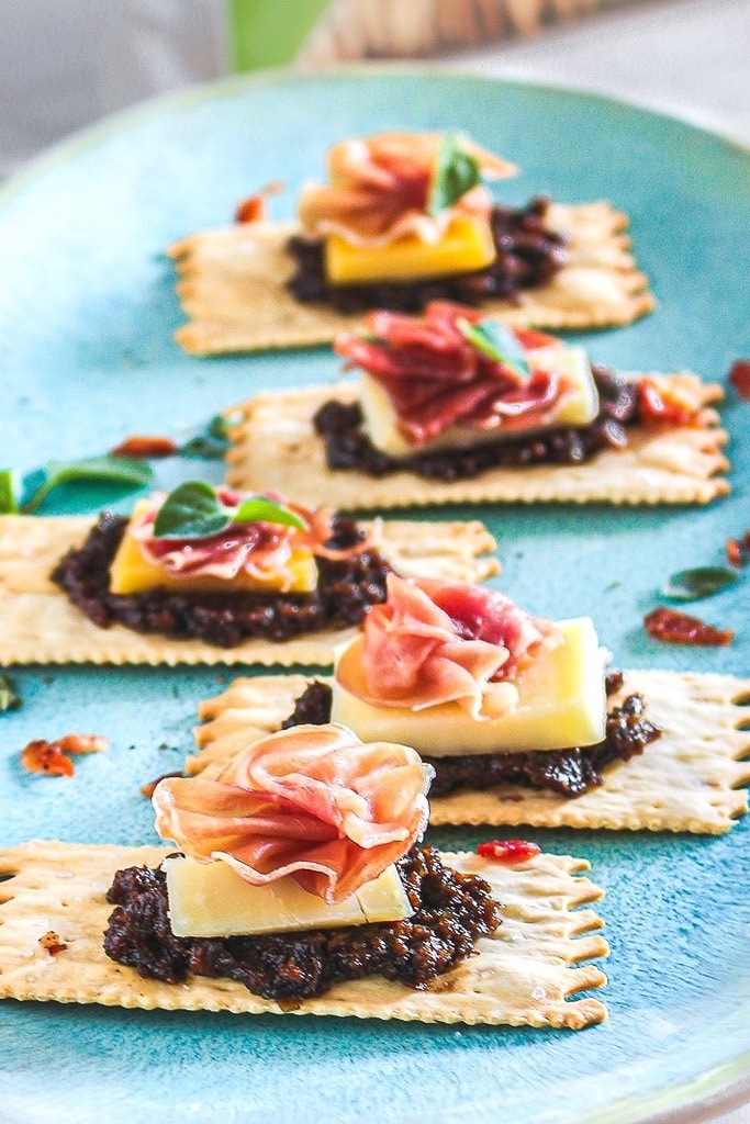 35 Party Appetizers For New Years Eve 10 croccantinis with apple bacon jam, gruyere cheese and prosciutto on top of blue serving tray