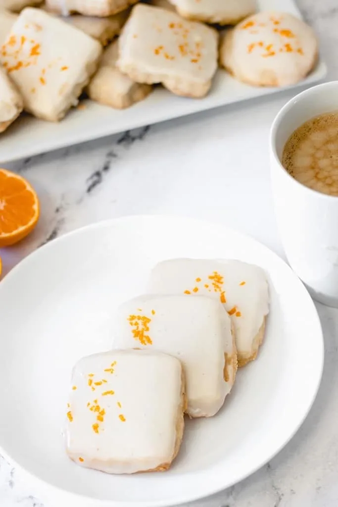 square cardamom shortbread cookies on white plate with orange topping 