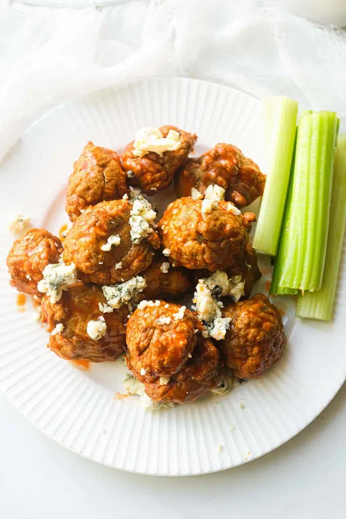 chicken meatballs covered in buffalo sauce and blue cheese crumbles with celery on the side 