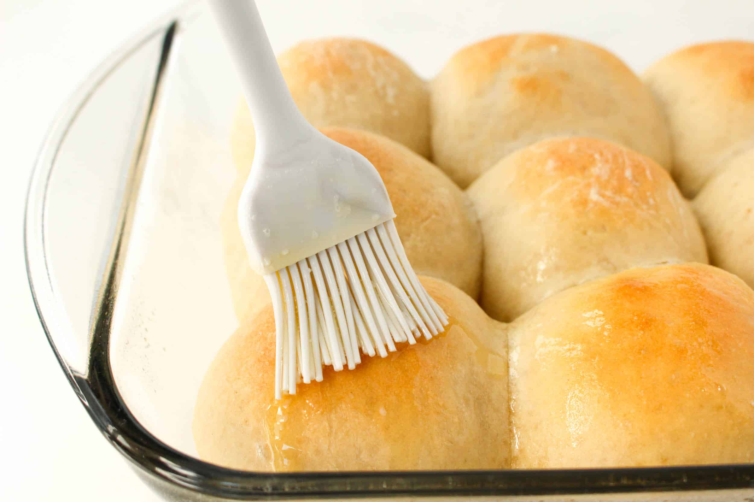 grey basting brush brushing butter on baked rolls 