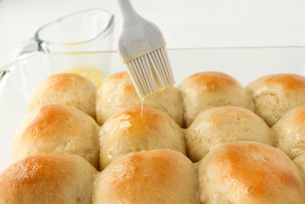 grey basting brush dripping butter on baked rolls 