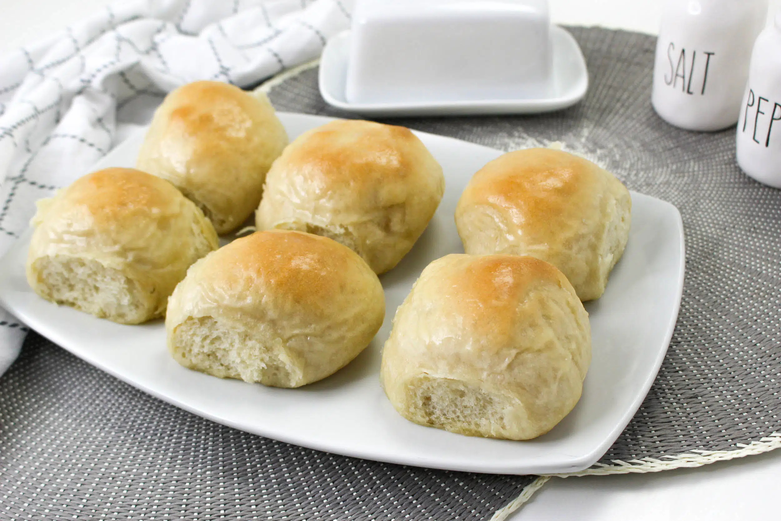 overhead view of 6 buttered rolls on white rectangle plate 