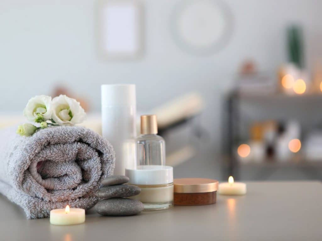The Best Spa in Gatlinburg, TN 2 Spa with rolled towel, candles, and flowers on a grey surface.