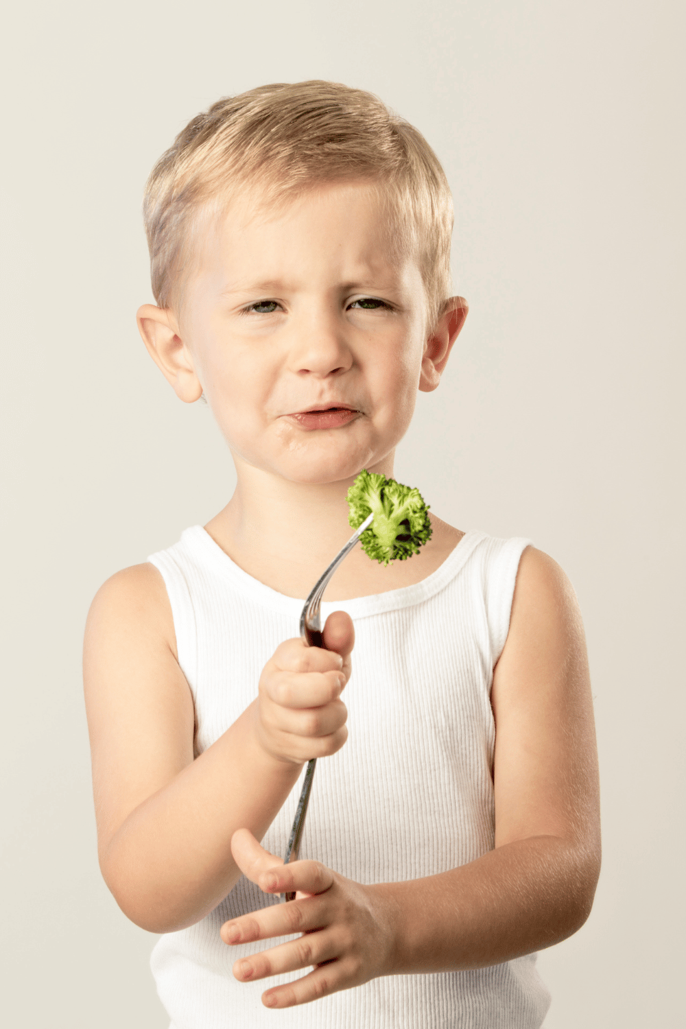 Top Tips For Visiting Disney World With A Picky Eater or Food Allergies 2 kid holding a piece of broccoli on a fork while making a sad face