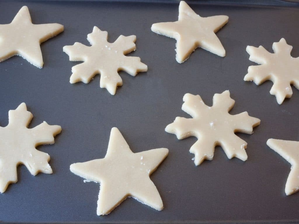Star & snowflake sugar cookie dough on a cookie sheet.