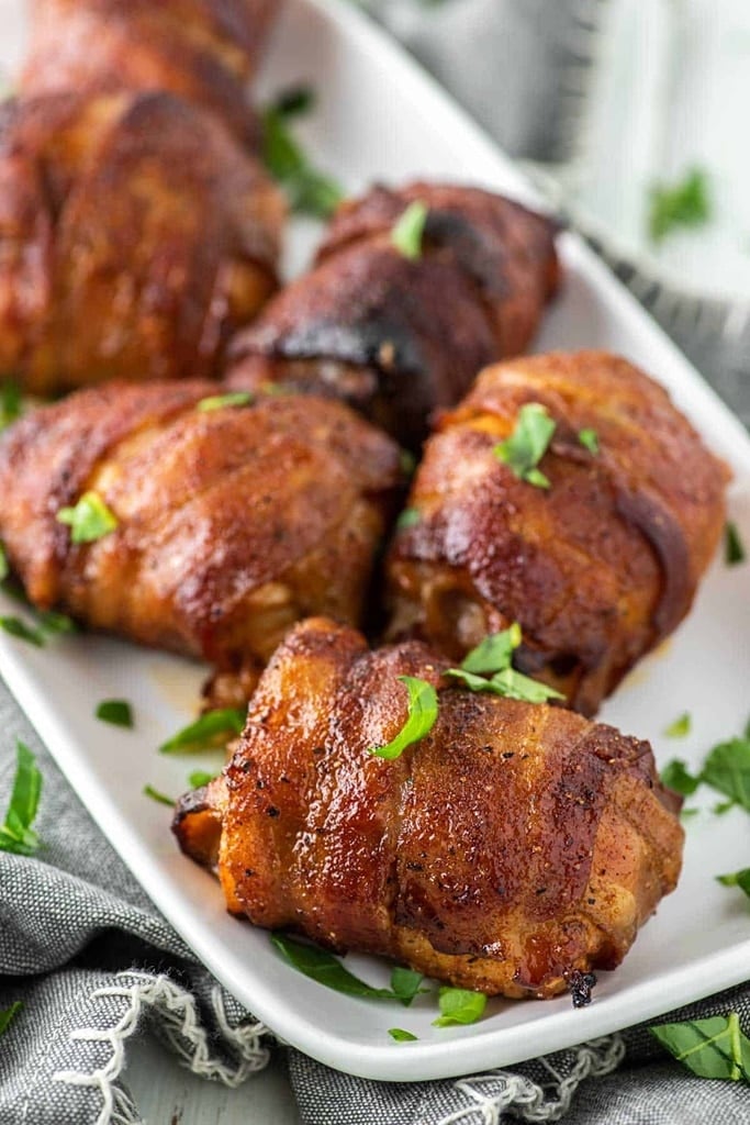 25 Boneless Skinless Chicken Thighs Recipes 2 chicken thighs wrapped in bacon on white plate