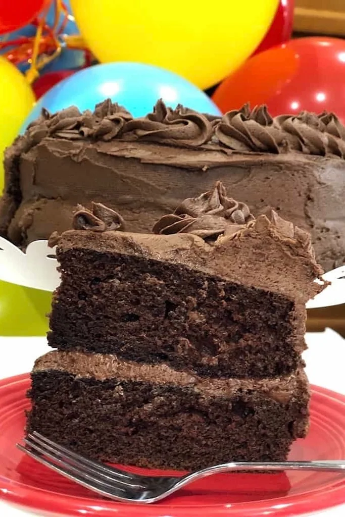 slice of chocolate cake on red plate with silver fork 